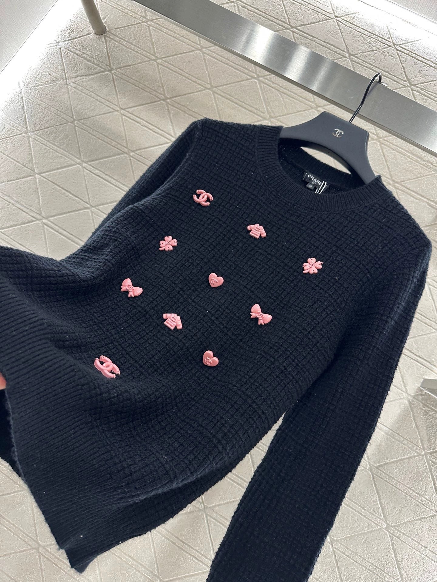 C 25 Un pull simple avec un logo et un détail de chaîne à la taille arrière. 