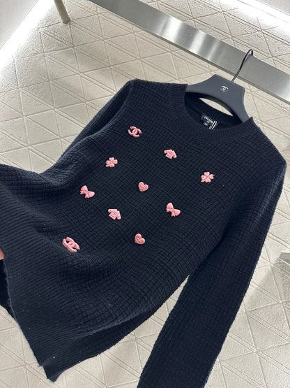 C 25 Un pull simple avec un logo et un détail de chaîne à la taille arrière. 