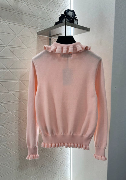 V 25 Long-sleeved knitted top with ruffled collar.
