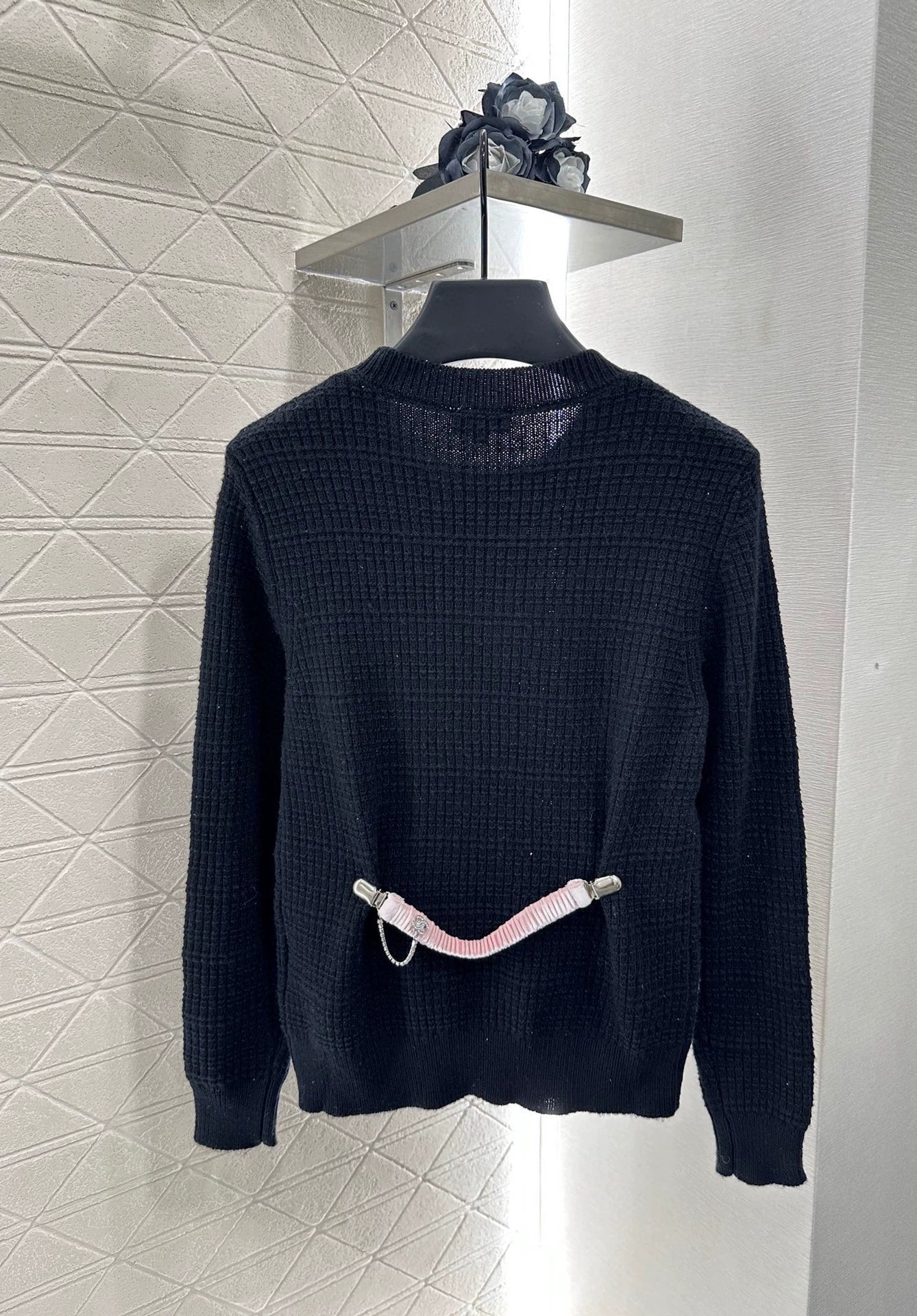 C 25 Un pull simple avec un logo et un détail de chaîne à la taille arrière. 