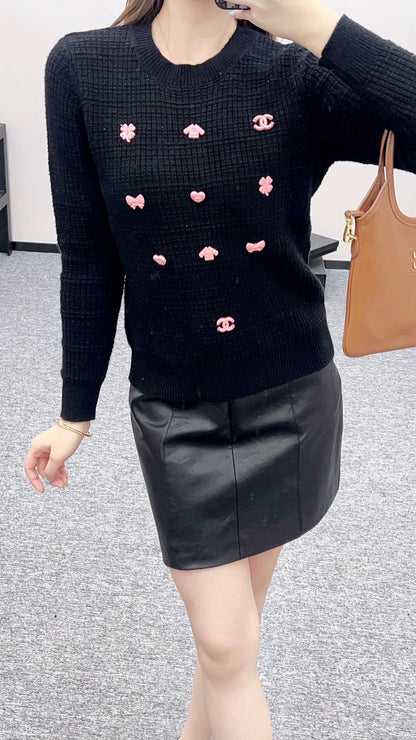 C 25 Un pull simple avec un logo et un détail de chaîne à la taille arrière. 