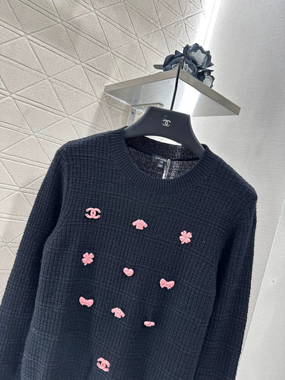 C 25 Un pull simple avec un logo et un détail de chaîne à la taille arrière. 