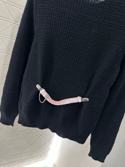 C 25 Un pull simple avec un logo et un détail de chaîne à la taille arrière. 