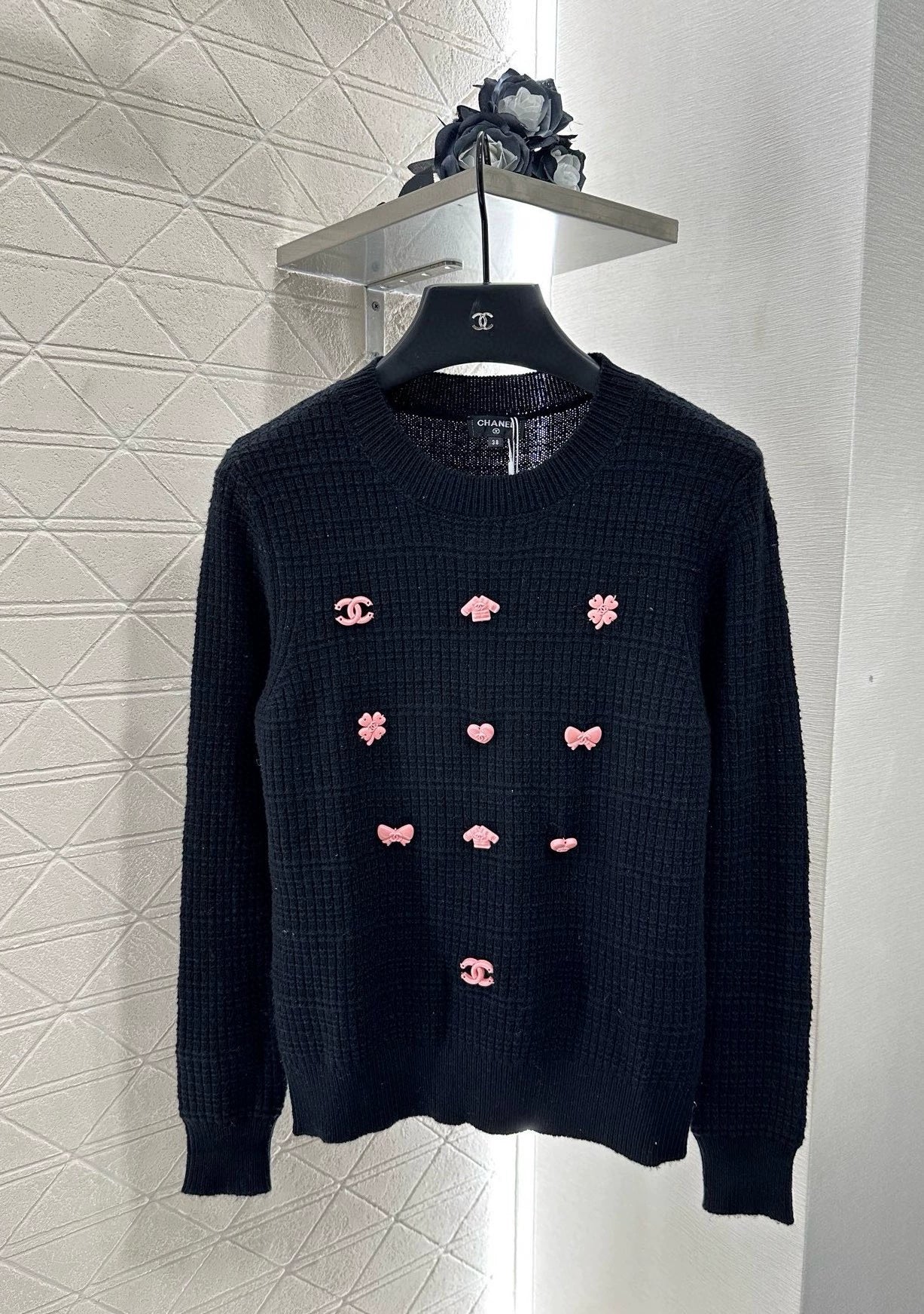 C 25 Un pull simple avec un logo et un détail de chaîne à la taille arrière. 